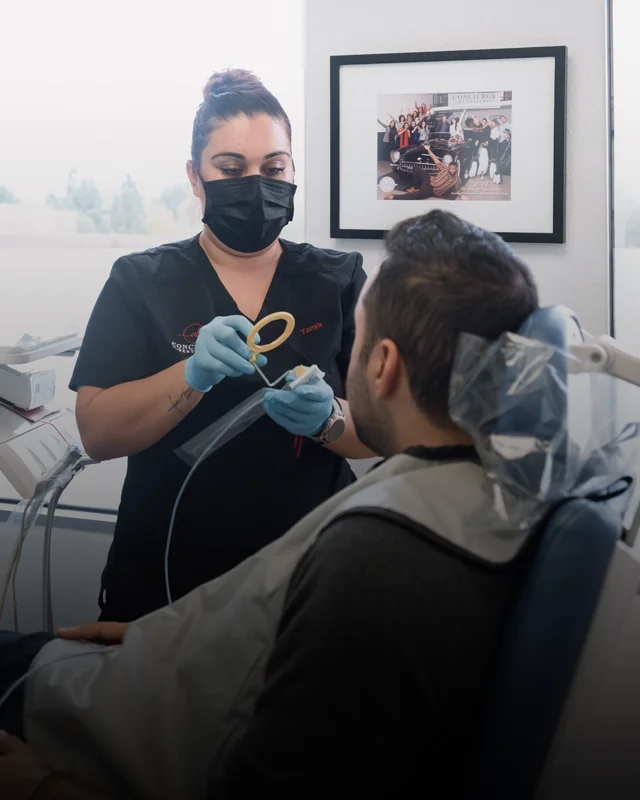 A dental hygienist discussing treatment with a patient during an exam