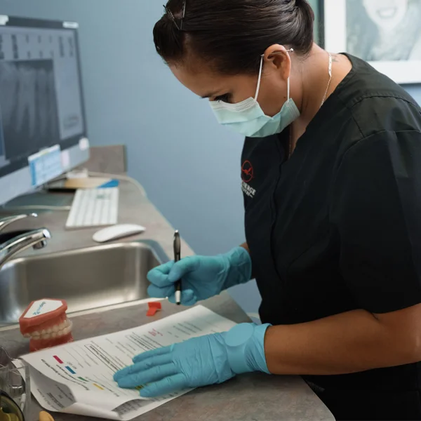 A dental assistant filling our patient paperwork during an appointment
