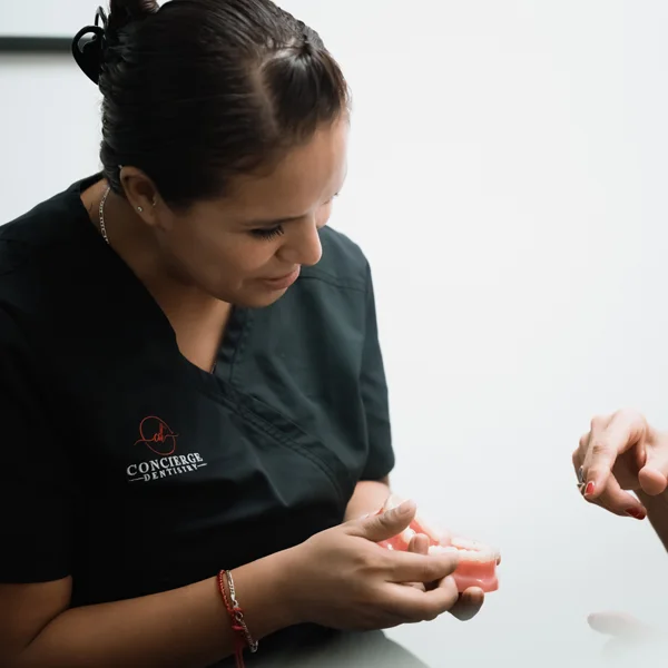 A patient pointing to a tooth model during a consultation